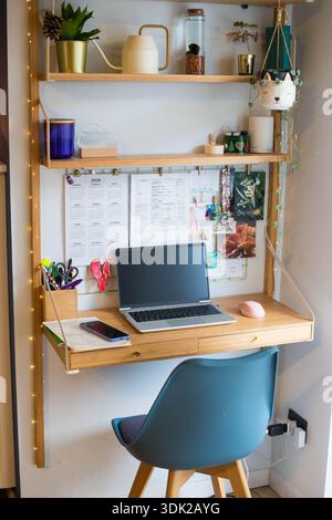 Stazione remota per piccoli uffici domestici, spazio di lavoro, con computer portatile, impianti domestici, pannello a parete e candele. Scatto verticale. Foto Stock