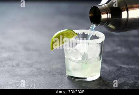 Il barista versa un cocktail di margarita al lime in un primo piano di bicchieri. Foto Stock