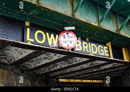 Marcatore di altezza circolare inglese e marcatore di ponte basso che mostrano l'altezza sia in Imperial che in Metric attaccati a un ponte ferroviario sul ponte. Foto Stock