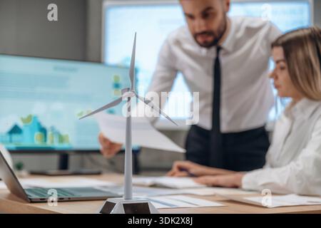 La donna è seduta, l'uomo è in piedi. Due dipendenti lavorano in un'azienda di turbine eoliche. Foto Stock