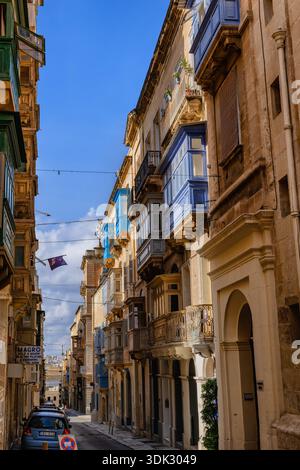 Città di la Valletta a Malta, tradizionali case maltesi con balconi lungo una stretta strada in pendenza. Foto Stock