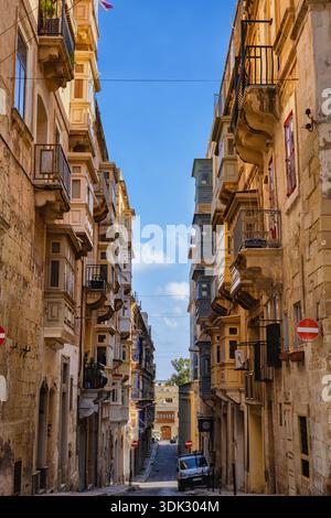 Città di la Valletta a Malta, tradizionali case maltesi con balconi lungo una stradina stretta. Foto Stock