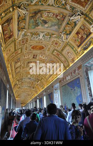 I visitatori camminano attraverso la galleria affollata all'interno dei Musei Vaticani, città del Vaticano Foto Stock