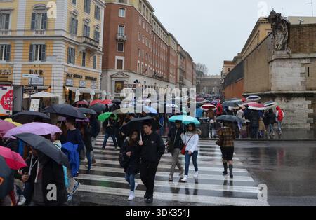 I pedoni attraversano la strada sotto la pioggia battente nel centro di Roma, Italia Foto Stock