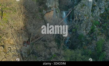 Vista aerea panoramica del canyon della Sierra Nevada, Spagna, con un lungo ponte in legno, una splendida cascata, un paesaggio naturale mozzafiato e montagne acquatiche Foto Stock