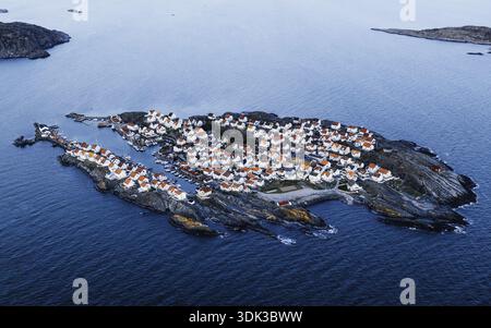 Vista aerea delle case bianche raggruppate dell'isola di Åstol con tetti rossi aggrappati alla costa rocciosa frastagliata, in contrasto con il mare blu profondo, Åstol Foto Stock