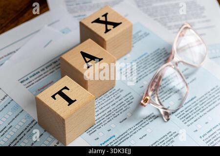 Dichiarazione dei redditi britannica. Regno Unito, moduli fiscali, TASSE scritte su blocchi di legno e occhiali da lettura. Concetto di business finanziario. Copia spazio, primo piano Foto Stock