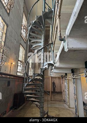 All'interno dello storico blocco di celle carcerarie con scala metallica a spirale, finestre sbarrate e dettagli di architettura industriale. Foto Stock