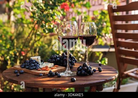 Due bicchieri di vino con tagliere di formaggio e uva Foto Stock