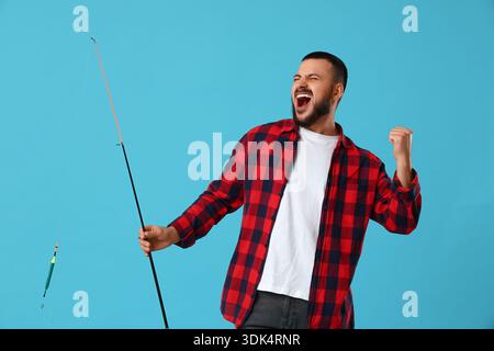 Giovane felice con canna da pesca su sfondo blu Foto Stock