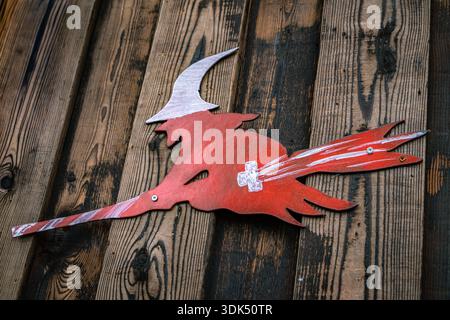 Silhouette rossa di una strega volante su una scopa con il simbolo della bandiera svizzera su una parete di legno per la sfilata di Carnevale invernale di Fasnacht a Zugo, Svizzera Foto Stock