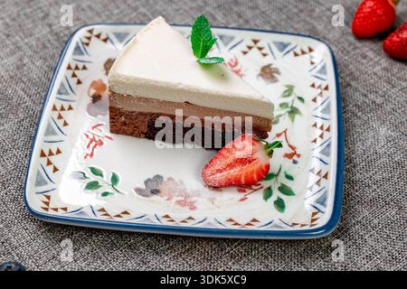 Squisito dessert a più strati "tre cioccolatini", leggero e arioso su un piatto bianco. Uno scatto verticale ravvicinato mette in mostra la delicata consistenza di scuri, Foto Stock