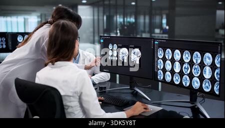 Neurologi qualificati analizzano attentamente le scansioni cerebrali per diagnosticare lesioni. Foto Stock