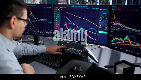 Broker di borsa ispanico che utilizza più monitor per il trading online. Foto Stock