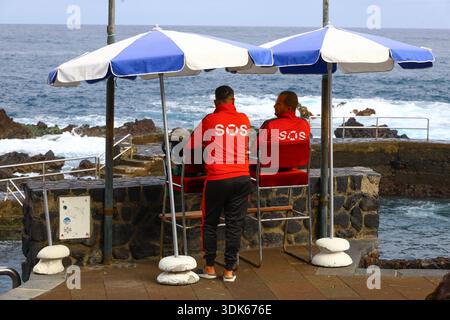 Puerto de la Cruz, Tenerife, 01152026 — bagnini SOS affacciati sulla costa rocciosa da sedie sopraelevate Foto Stock