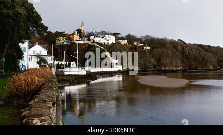 Vista panoramica dei colorati edifici italiani di Portmeirion e della torre del Campanile che si innalza sopra le colline boscose, riflessa nelle acque dell'estuario di Dwyryd Foto Stock