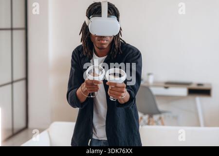 Concentrati sul gioco. Uomo nero con occhiali per realtà virtuale a casa. Foto Stock
