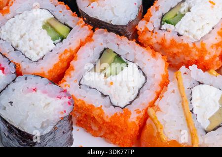 Coloratissimi sushi in contenitore da asporto con contrasti di nori e riso, ripieni di avocado e panna visibili, veloce opzione di pasto urbano presentato dall'alto Foto Stock