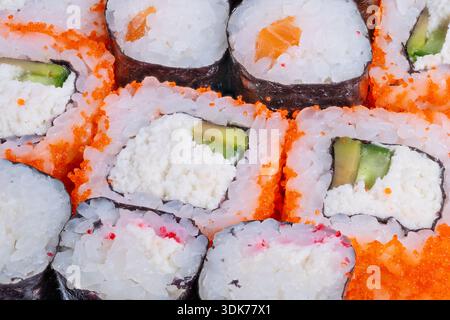 primi piani di sushi con uova d'arancia, formaggio spalmabile e ripieno di avocado, grani di riso lucidi e bordi nori, illuminazione luminosa da studio, shot food stylist Foto Stock