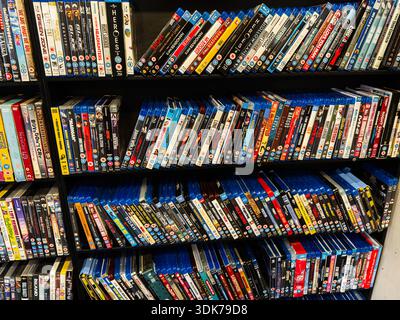 Manchester, Regno Unito - 21 gennaio 2026: Un affollato scaffale di DVD e raggi blu, che presenta una vivace collezione di film. Foto Stock