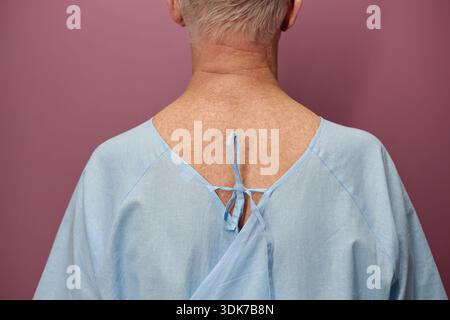 Uomo anziano che indossa l'abito da ospedale in attesa di esame vascolare Foto Stock