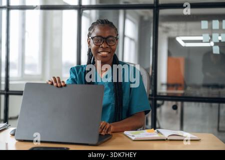 Notebook color argento. La dottoressa donna in giacca è nella clinica dell'ufficio. Foto Stock