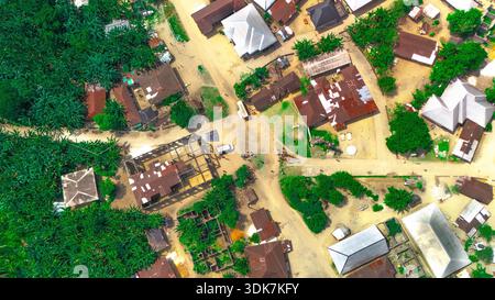 La vista aerea del villaggio mostra i colori vivaci dei tetti che contrastano con il lussureggiante fogliame verde, creando un effetto patchwork quilt., Otaba Foto Stock