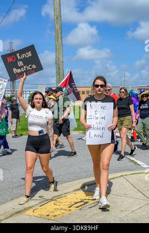 New Orleans, LOUISIANA, Stati Uniti - 14 giugno 2025: No Kings Marchers con due giovani donne in primo piano che recano "No Kings in America from 1776" e "No One is illegal on Stolen Land" Foto Stock