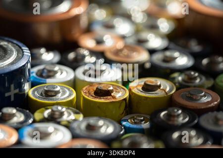 Primo piano delle estremità positive delle batterie scariche di diverse dimensioni e formati, messa a fuoco selettiva. Batteria alcalina usata con corrosione e ruggine. Concetto di spazzatura pericolosa Foto Stock