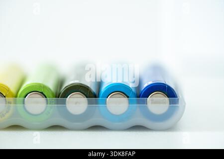 Nuova batteria AAA colorata in scatola di plastica, primo piano dell'accumulatore ricaricabile, foto macro di batterie alcaline su sfondo bianco, messa a fuoco morbida selettiva. Concetto di riciclaggio ecologico. Foto Stock