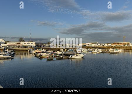 Ampia vista panoramica del porto turistico e del porto di Olhao, Algarve, Portogallo. Le piccole barche sono ormeggiate su acque blu calme vicino all'ingresso del porto, con po Foto Stock