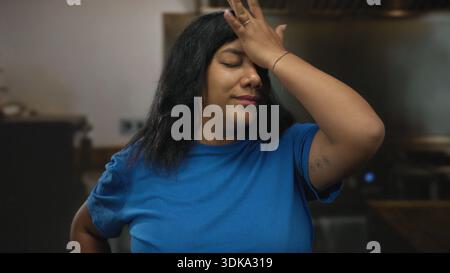 La donna stringe il naso in cucina sul piano di lavoro in legno chiudendo gli occhi e inclinando la testa all'indietro; disgusto. Foto Stock