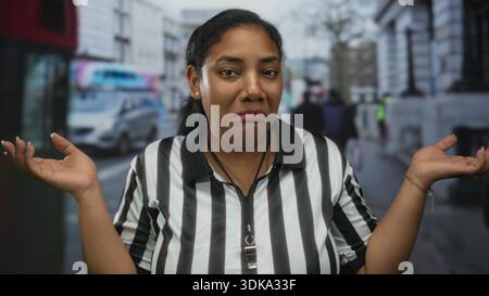 La donna dell'arbitro toglie le palme sulla strada trafficata di fronte a un autobus rosso di passaggio e ai pedoni sfocati; incertezza. Foto Stock