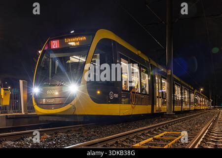 Moderno tram giallo U-OV di notte a Utrecht, Paesi Bassi. Esposizione lunga che mostra i fari sulle tracce. Trasporto pubblico urbano in città. Utrecht Foto Stock