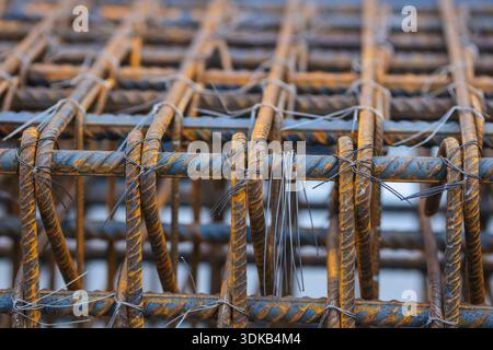 Dettagli della profondità di campo bassa (messa a fuoco selettiva) con barre di rinforzo (armature) in cantiere. Foto Stock