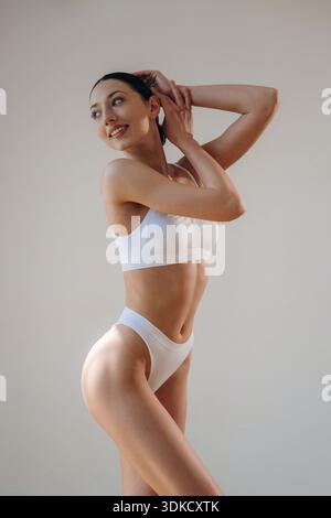 Vista laterale. Una giovane donna in abiti sportivi è contro il muro. Foto Stock