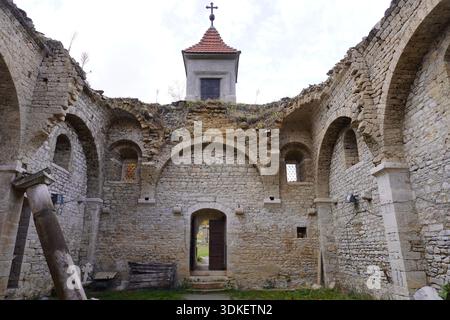 Vecchia chiesa di San Nicola vicino al lago Mavrovo, Macedonia del Nord, parzialmente sommersa in passato, circondata da alberi autunnali, con esterno e interno vi Foto Stock