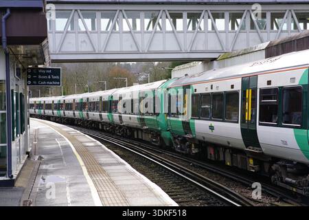Treno verde Southern Class 377 che si trova sulla piattaforma curva sotto il ponte pedonale della stazione di Redhill. Redhill, Inghilterra Foto Stock