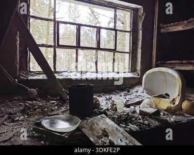 Edificio abbandonato con finestra coperta di neve e vista sulla foresta Foto Stock