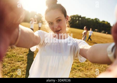 Guardando la fotocamera, facendo selfie. I giovani amici si stanno divertendo sul campo. Foto Stock