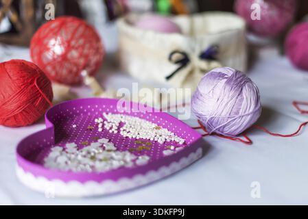 Decorazioni a forma di cuore e palle di filato sono su una tovaglia bianca Foto Stock