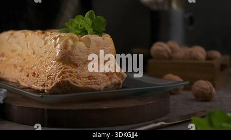 Un tradizionale dessert portoghese Molotov si siede su un piatto di vetro, caratterizzato da una consistenza dorata al forno condita con caramello ambrato. Il moody, dai toni scuri Foto Stock