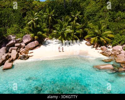 Coppia che si gode un momento romantico sulle coste incontaminate dell'Anse Lazio. Circondato da vegetazione lussureggiante e acque turchesi, questo gioiello nascosto a Seychelle Foto Stock