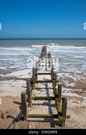 Onde che si infrangono su un groyne di legno a zigzagging a Overstrand Beach, Overstrand, Norfolk, East Anglia, Inghilterra, Regno Unito, in una brillante giornata estiva nel 2025. Foto Stock