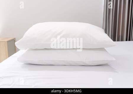 Due cuscini bianchi in pila sul letto sono serviti in hotel o nelle camere resort. Foto Stock