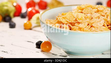 Presentazione stilizzata di una sana colazione con cereali croccanti e frutti di bosco maturi su un tavolo rustico Foto Stock