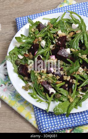 Cibo, insalata di barbabietole con rucola con feta e capperi, cosparsa di noci tritate Foto Stock