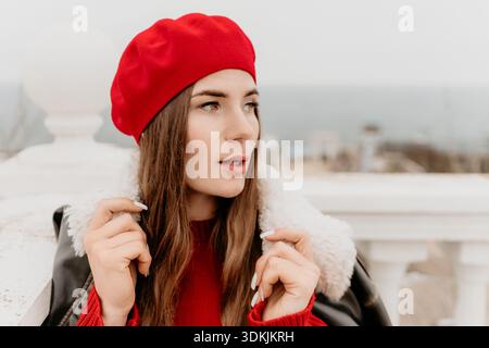 Ritratto di una donna beretta. Una giovane donna elegante in berretto rosso e una comoda giacca è attenta all'esterno. Foto Stock