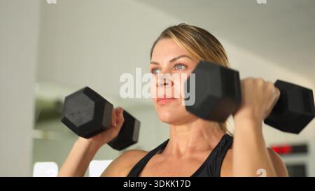 Donna che si allena con i manubri per l'allenamento di forza Foto Stock