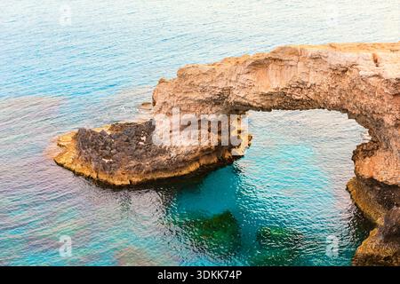 Formazione ad arco naturale del Ponte dell'amore situato nel Parco Nazionale forestale di Capo Greco ad Ayia Napa, Cipro, nelle acque turchesi del Mediterraneo. monumento naturale Foto Stock